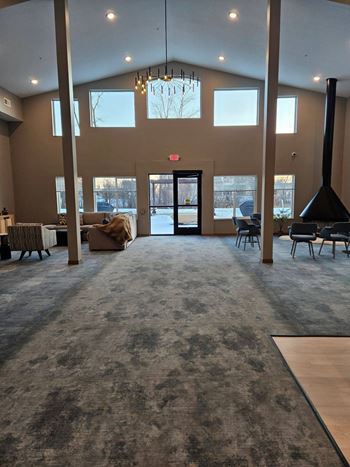 A large room with a grey carpet and a chandelier hanging from the ceiling.